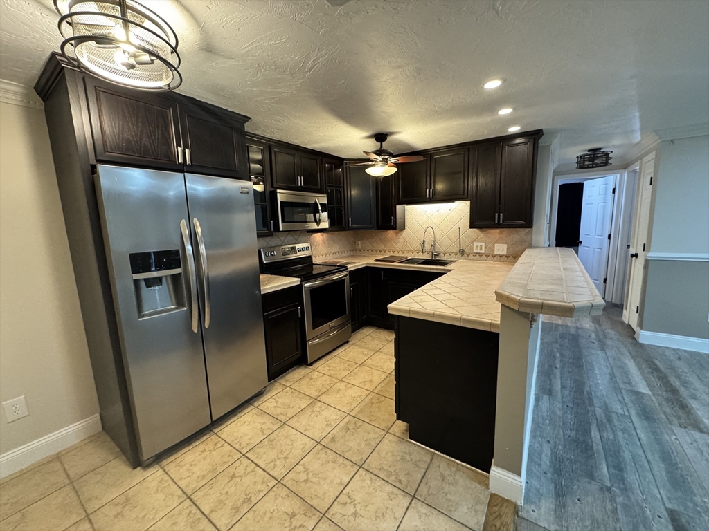 1619 Braley Road, Unit 98 New Bedford, MA 02745 - Photo 10 of 32 a kitchen with stainless steel appliances granite countertop a refrigerator a sink a stove and island