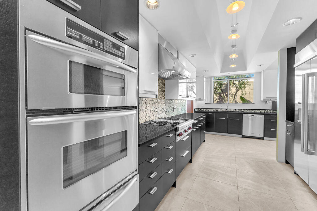 1421 Tamarisk W Street, Unit 3 Rancho Mirage, CA 92270 - Photo 39 of 65 a kitchen with stainless steel appliances kitchen island granite countertop a stove and a sink