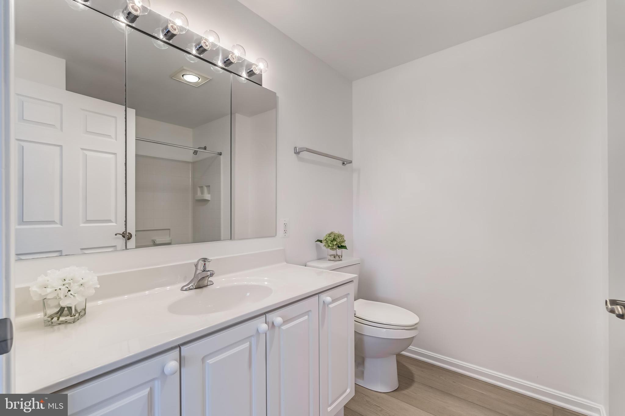 19355 Cypress Ridge Terrace, Unit 114 Leesburg, VA 20176 - Photo 28 of 42 a bathroom with a granite countertop sink a toilet and a mirror