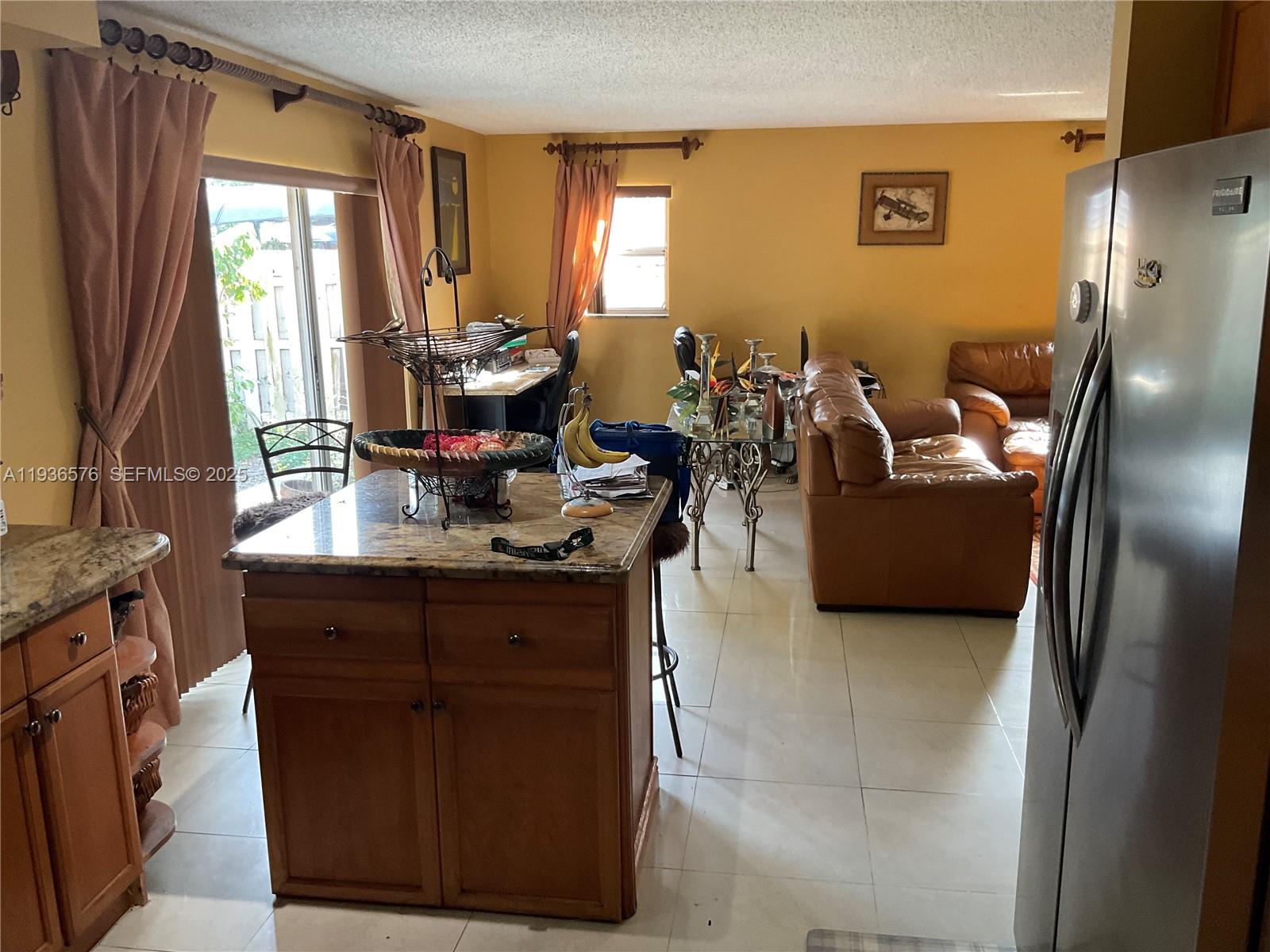 3161 Venice Way Miramar, FL 33025 - Photo 12 of 37 a living room with couches a flat tv screen and a refrigerator