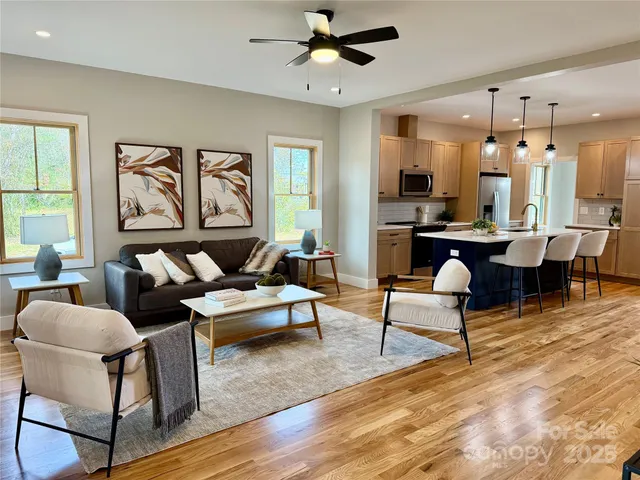 a living room with furniture kitchen view and a large window