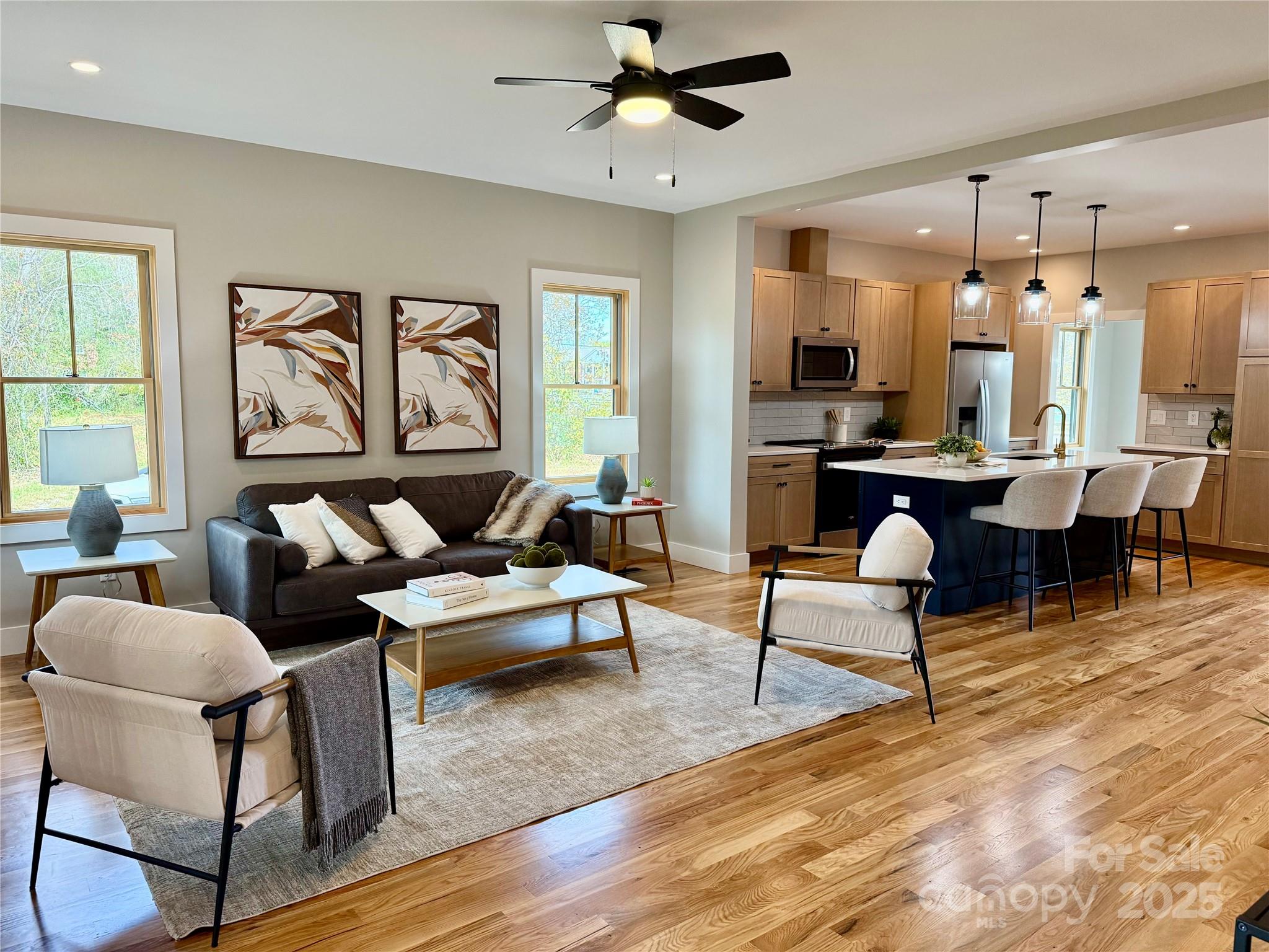 a living room with furniture kitchen view and a large window