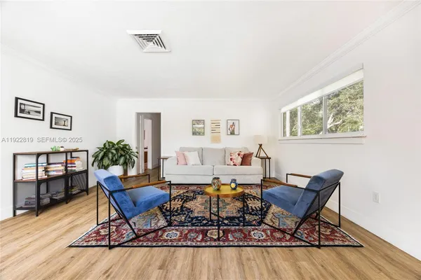 a living room with furniture a rug potted plant and wooden floor