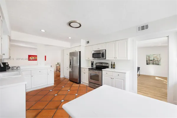 a large kitchen with kitchen island a sink stainless steel appliances and cabinets
