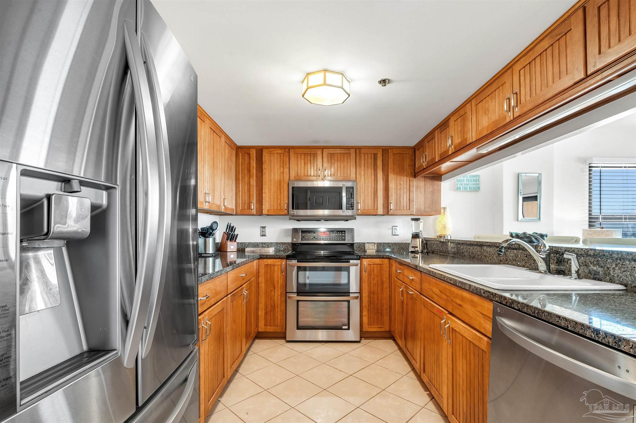 13817 Perdido Key Drive, Unit 501 Pensacola, FL 32507 - Photo 30 of 63 a kitchen with stainless steel appliances granite countertop a sink stove microwave and refrigerator