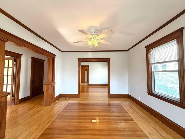 a view of an empty room with window and wooden floor