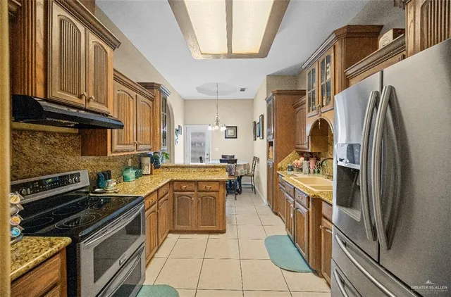a kitchen with stainless steel appliances granite countertop a refrigerator a stove and a sink