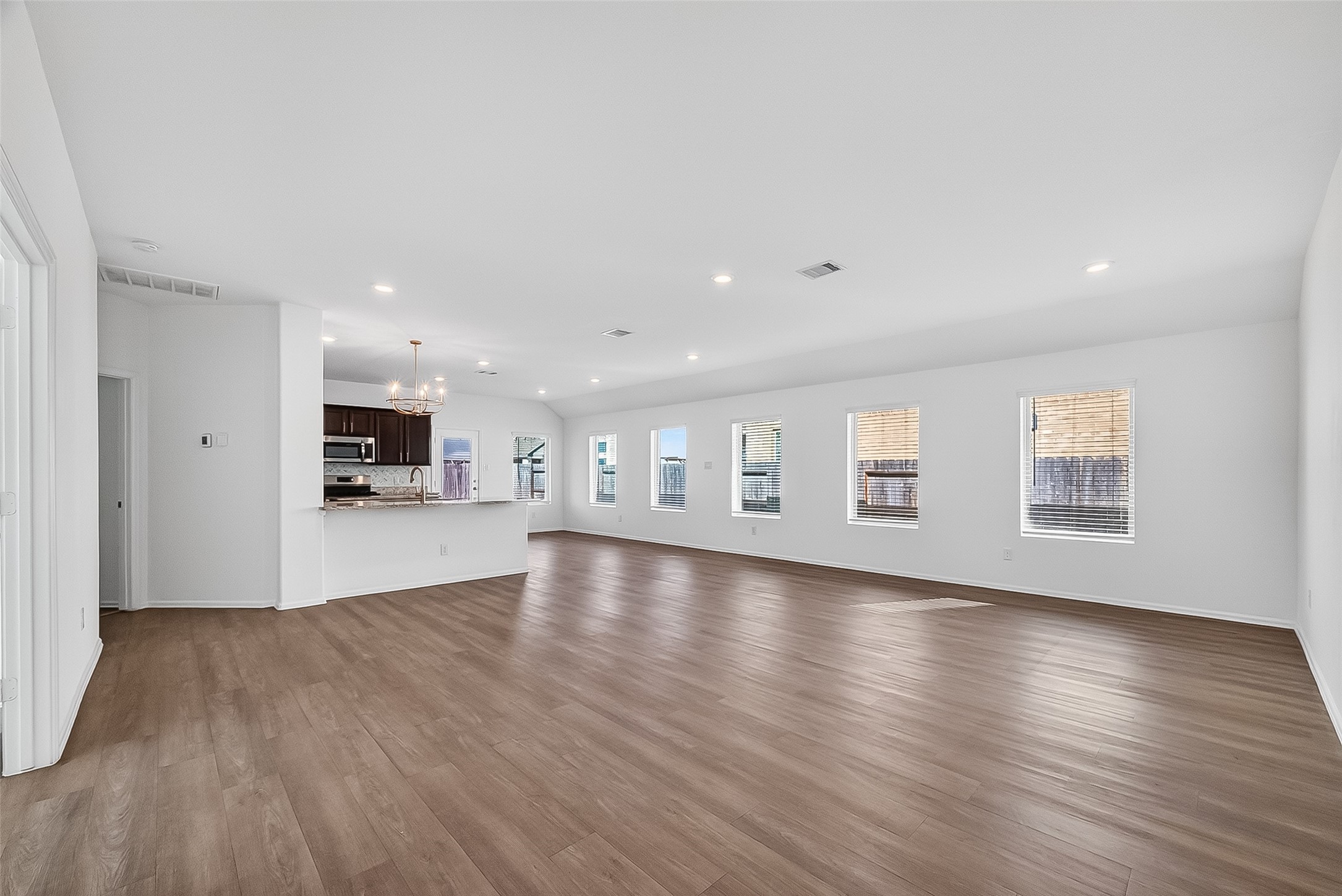 19168 Pinewood Grove Trail New Caney, TX 77357 - Photo 15 of 41 a view of empty room with wooden floor and a kitchen
