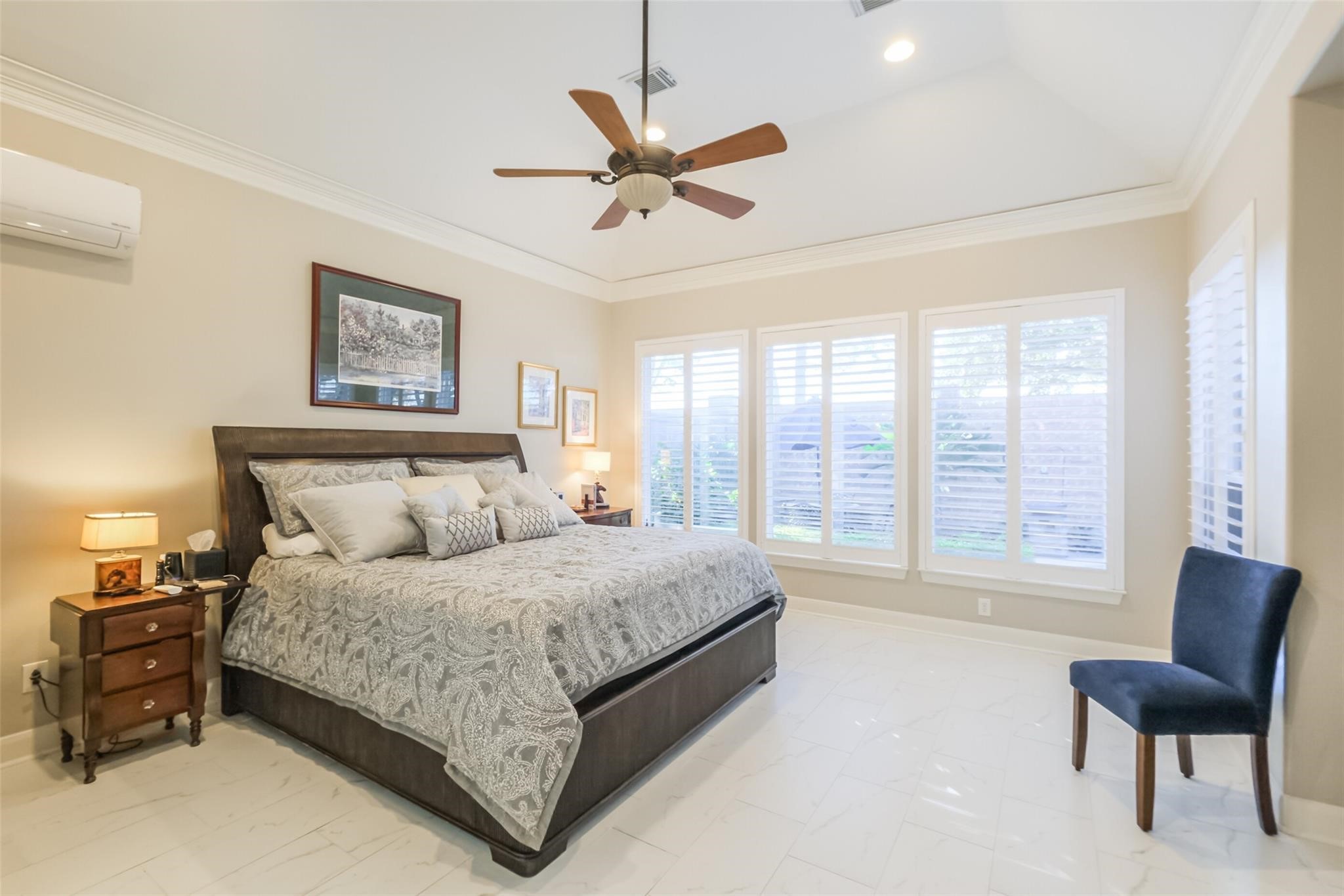 11413 Gallant Ridge Lane Houston, TX 77082 - Photo 32 of 50 Spacious and bright bedroom featuring a large bed, elegant furnishings, and ample natural light from multiple windows with plantation shutters. The room includes a ceiling fan and a modern, neutral color palette, creating a serene and inviting atmosphere. Personal property not included with sale