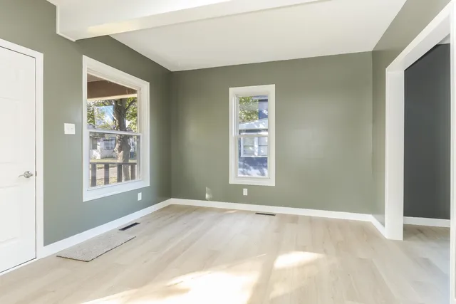 a view of an empty room with wooden floor and windows