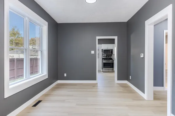 a view of an empty room with wooden floor and a window