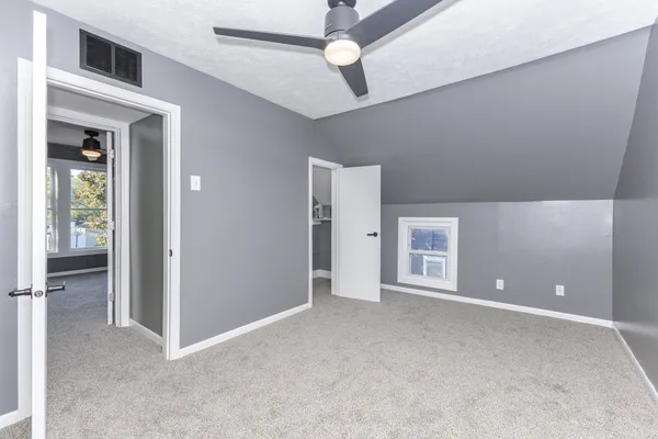 an empty room with windows and fan