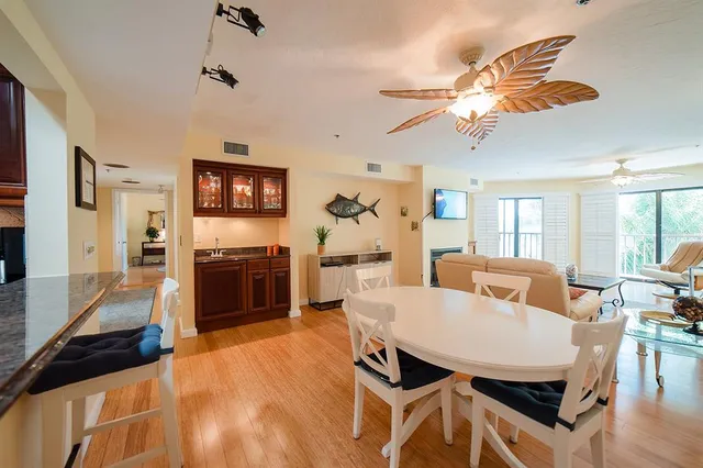 a living room with couches chairs and a dining table with wooden floor