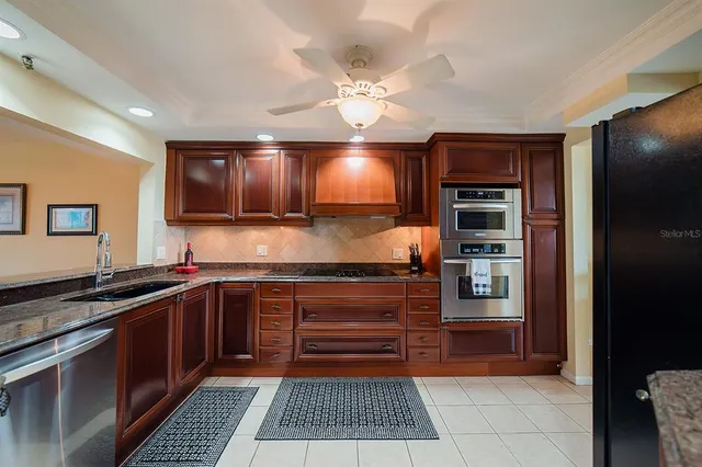 a kitchen with stainless steel appliances granite countertop a sink a stove and cabinets