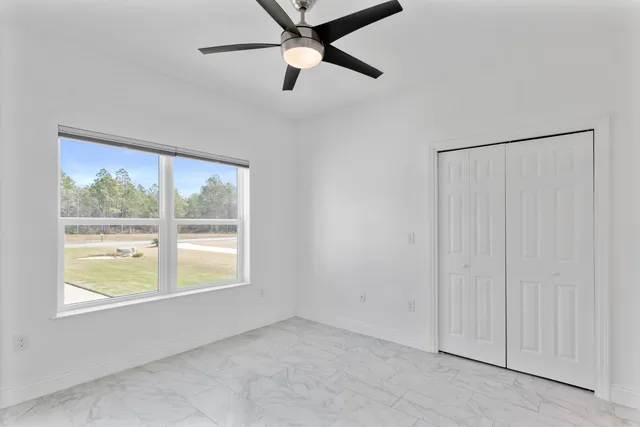 a view of an empty room with wooden floor and windows