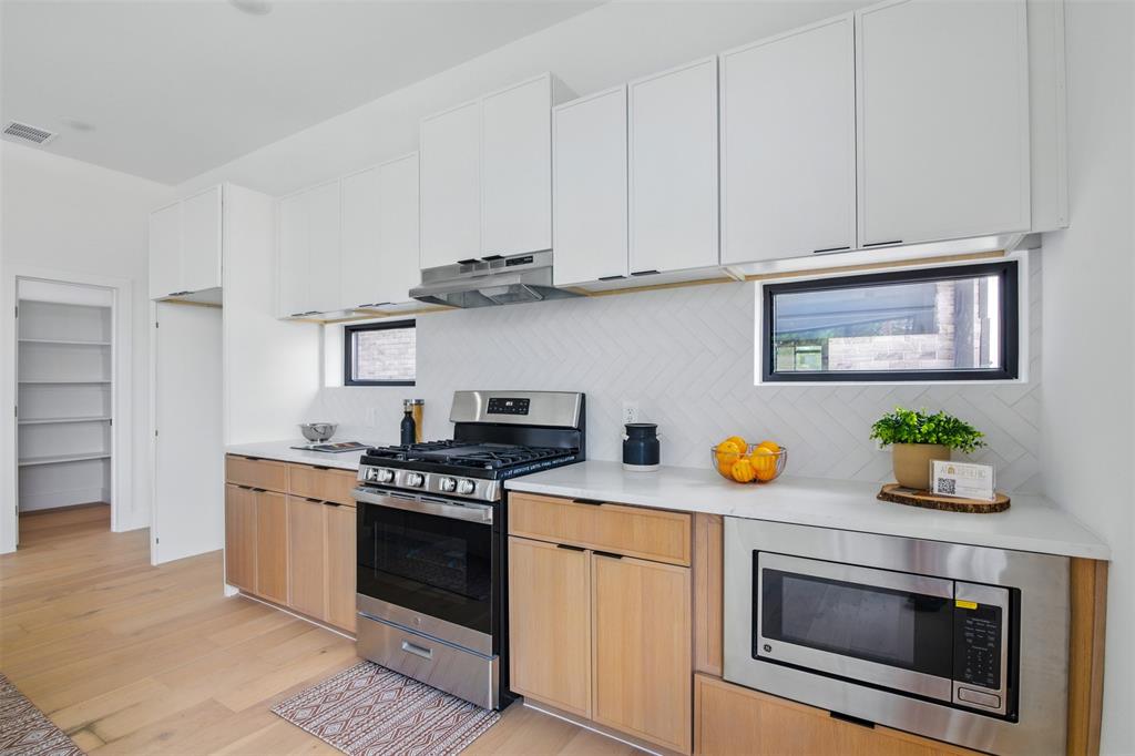 430 East 8th Street, Unit 201 Dallas, TX 75203 - Photo 12 of 26 a kitchen with stainless steel appliances granite countertop a stove a microwave and cabinets