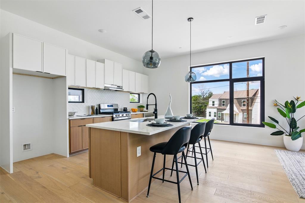 430 East 8th Street, Unit 201 Dallas, TX 75203 - Photo 7 of 26 a kitchen with stainless steel appliances granite countertop sink stove and white cabinets with wooden floor