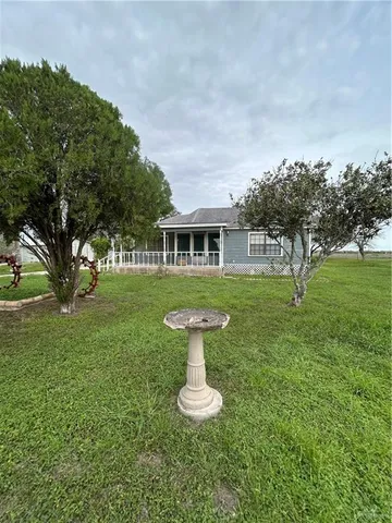 a view of a house with a yard fire pit and a large tree