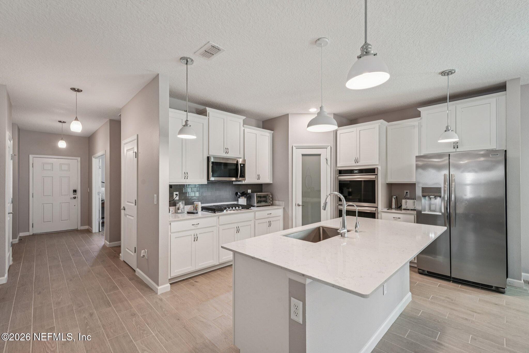 75682 Pondside Lane Yulee, FL 32097 - Photo 11 of 35 a kitchen with kitchen island a refrigerator a stove a microwave oven a sink with island and chairs