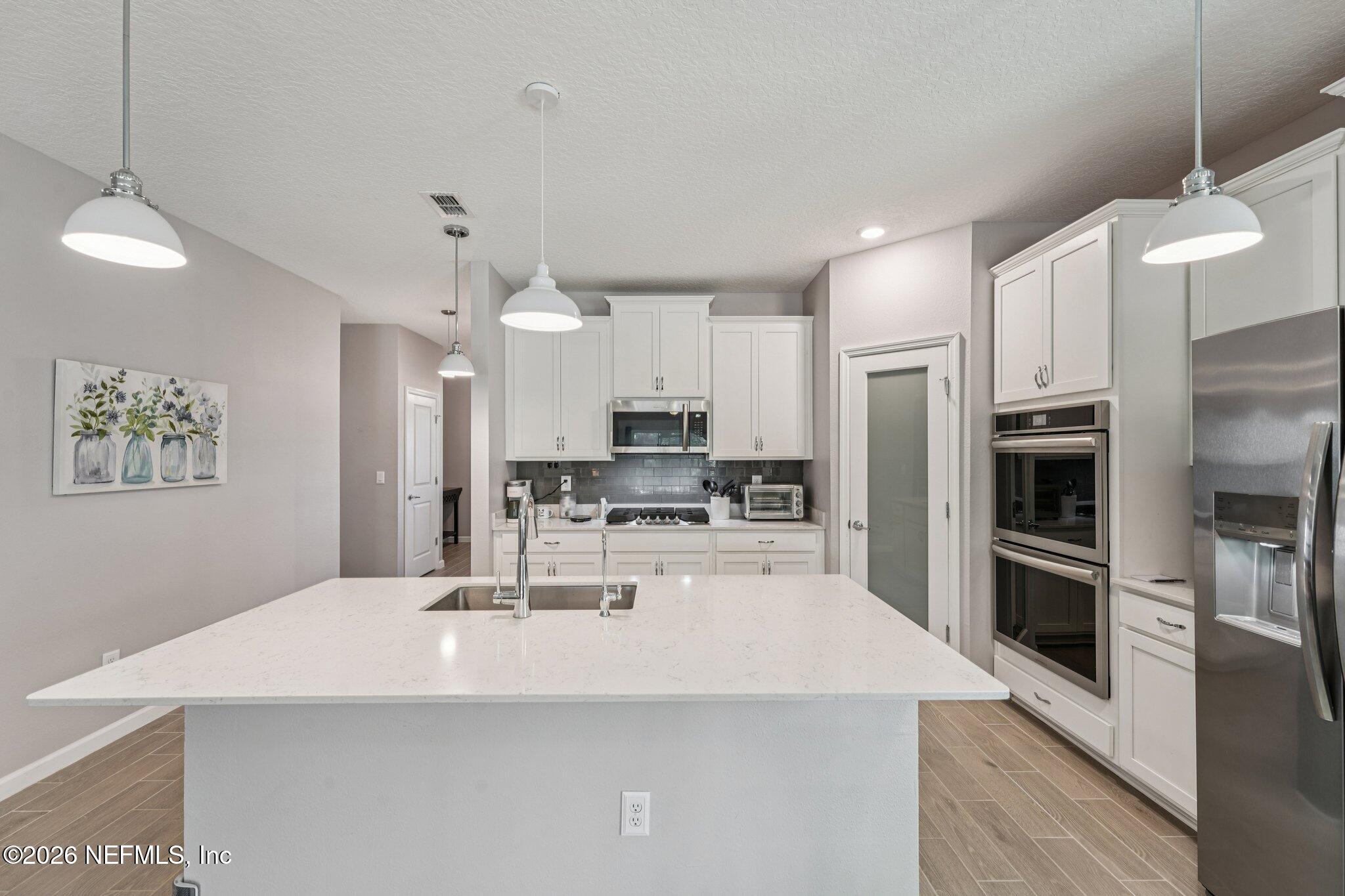 75682 Pondside Lane Yulee, FL 32097 - Photo 13 of 35 a kitchen with kitchen island a counter top space stainless steel appliances and cabinets