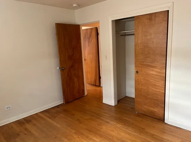 an empty room with wooden floor and closet area
