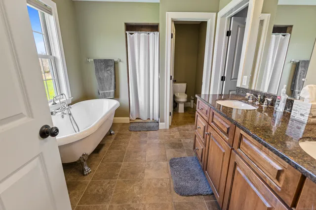 a spacious bathroom with a tub a sink and a large mirror