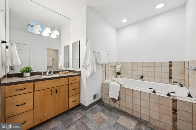 a spacious bathroom with a double vanity sink a large mirror and bathtub