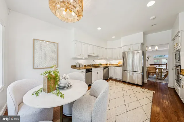 a kitchen with stainless steel appliances kitchen island granite countertop a table chairs and a refrigerator