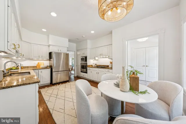 a kitchen with stainless steel appliances granite countertop a refrigerator a stove a sink dishwasher a dining table and chairs with wooden floor