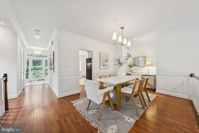 a dining room with wooden floor a chandelier a wooden table and chairs