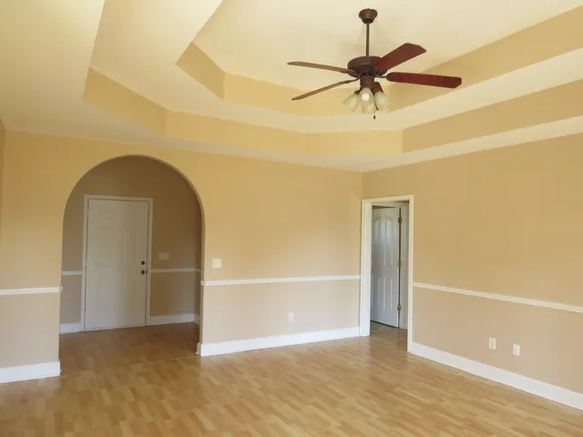 a view of empty room with wooden floor and ceiling fan