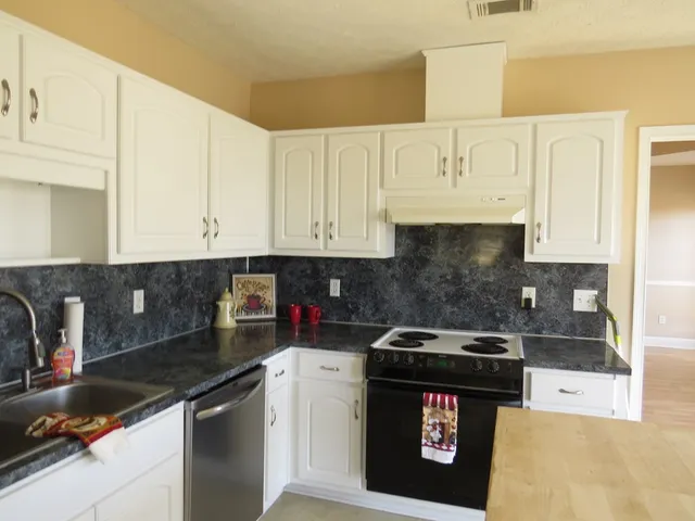 a kitchen with granite countertop white cabinets and stainless steel appliances