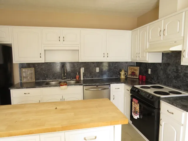 a kitchen with granite countertop a sink a stove and cabinets