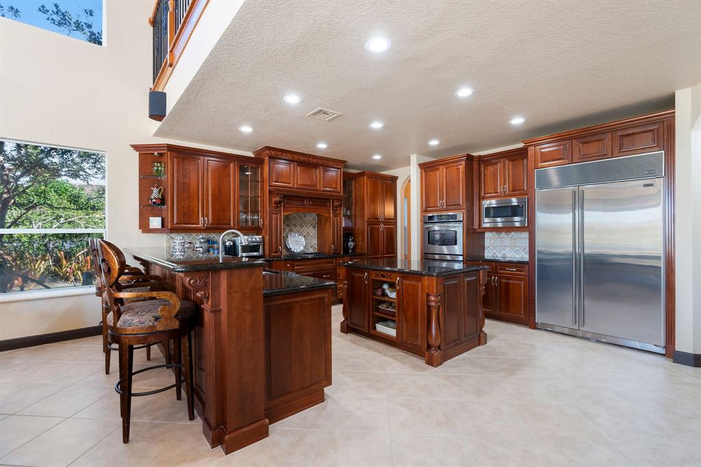 3413 Dovecote Meadow Lane Davie, FL 33328 - Photo 18 of 68 a kitchen with stainless steel appliances kitchen island granite countertop a refrigerator and a wooden cabinets