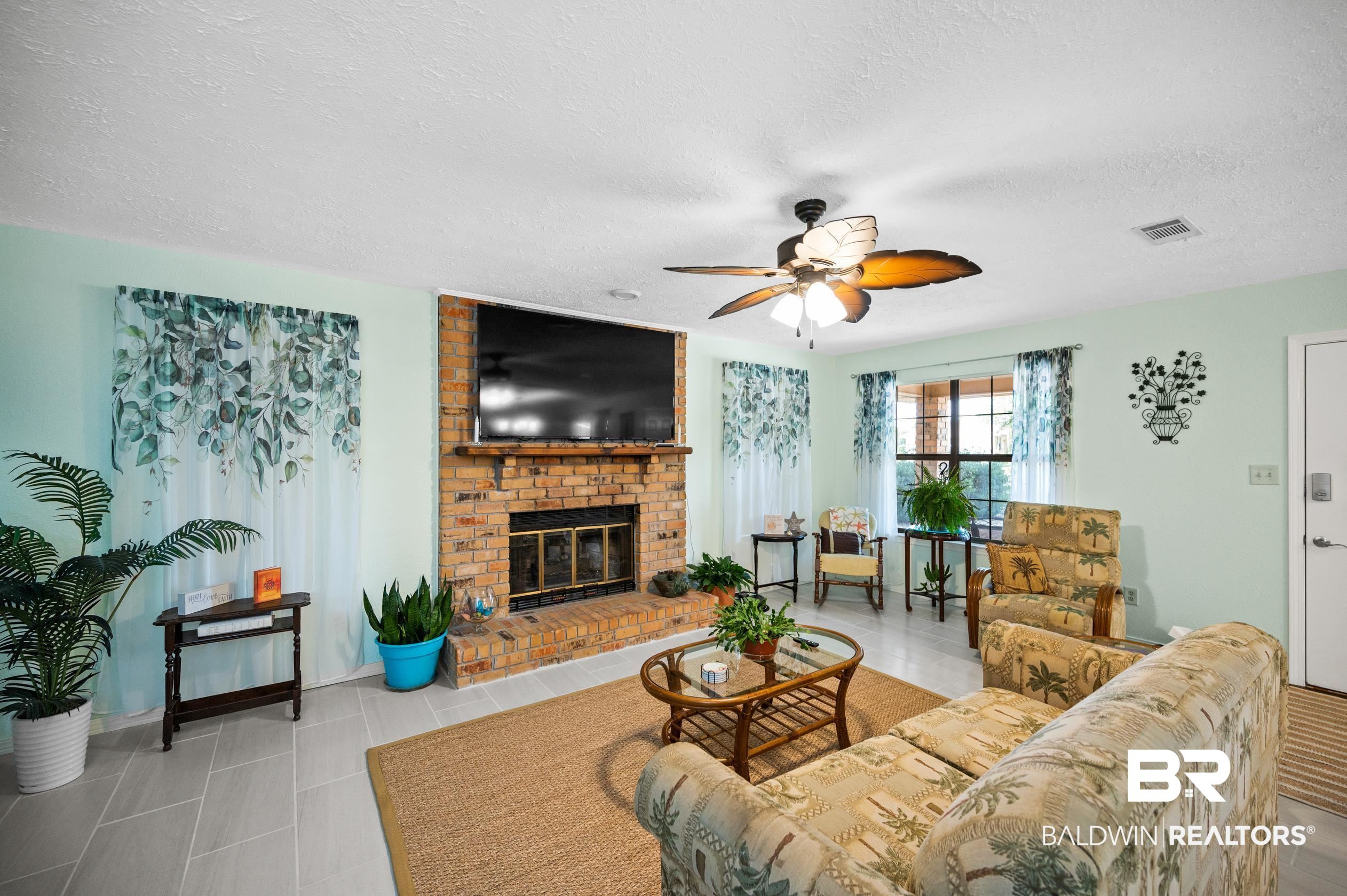 2772 Santa Rosa Circle Lillian, AL 36549 - Photo 8 of 50 Living room featuring a fireplace, light tile patterned floors, a textured ceiling, brick wall, and ceiling fan