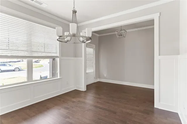 an empty room with wooden floor chandelier and windows