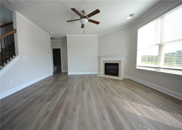 a view of an empty room with a window and wooden floor