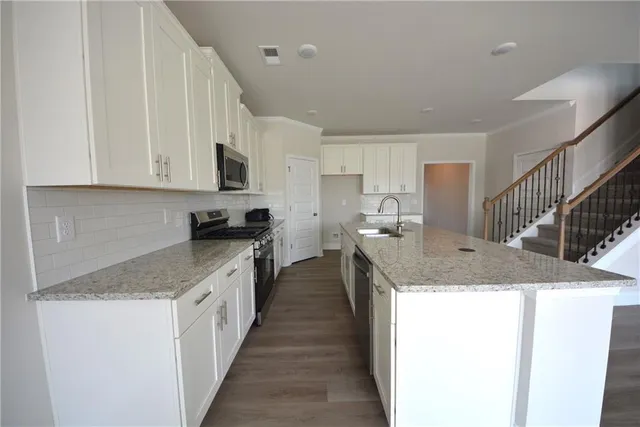 a kitchen with stainless steel appliances granite countertop a sink stove and cabinets