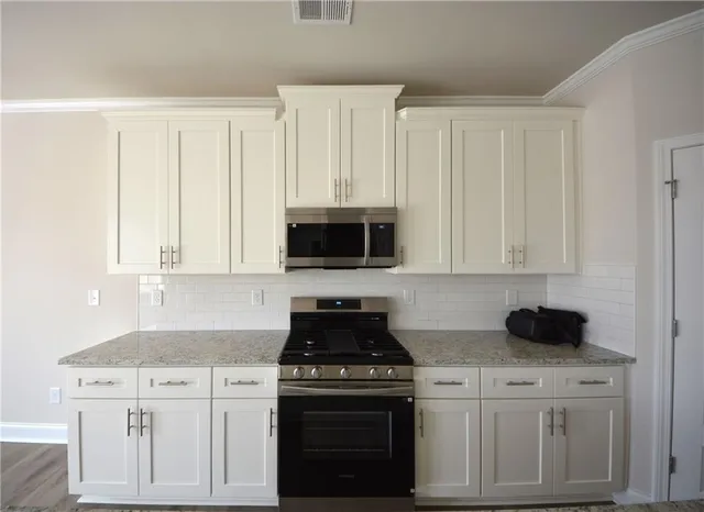 a kitchen with white cabinets and black appliances