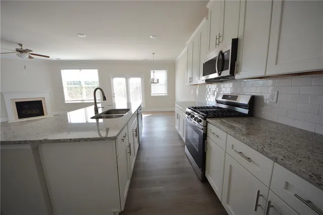 a kitchen with stainless steel appliances granite countertop a sink a stove top oven a counter space and cabinets