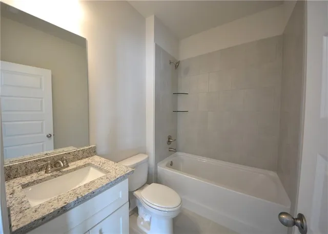 a bathroom with a granite countertop sink a toilet and bathtub