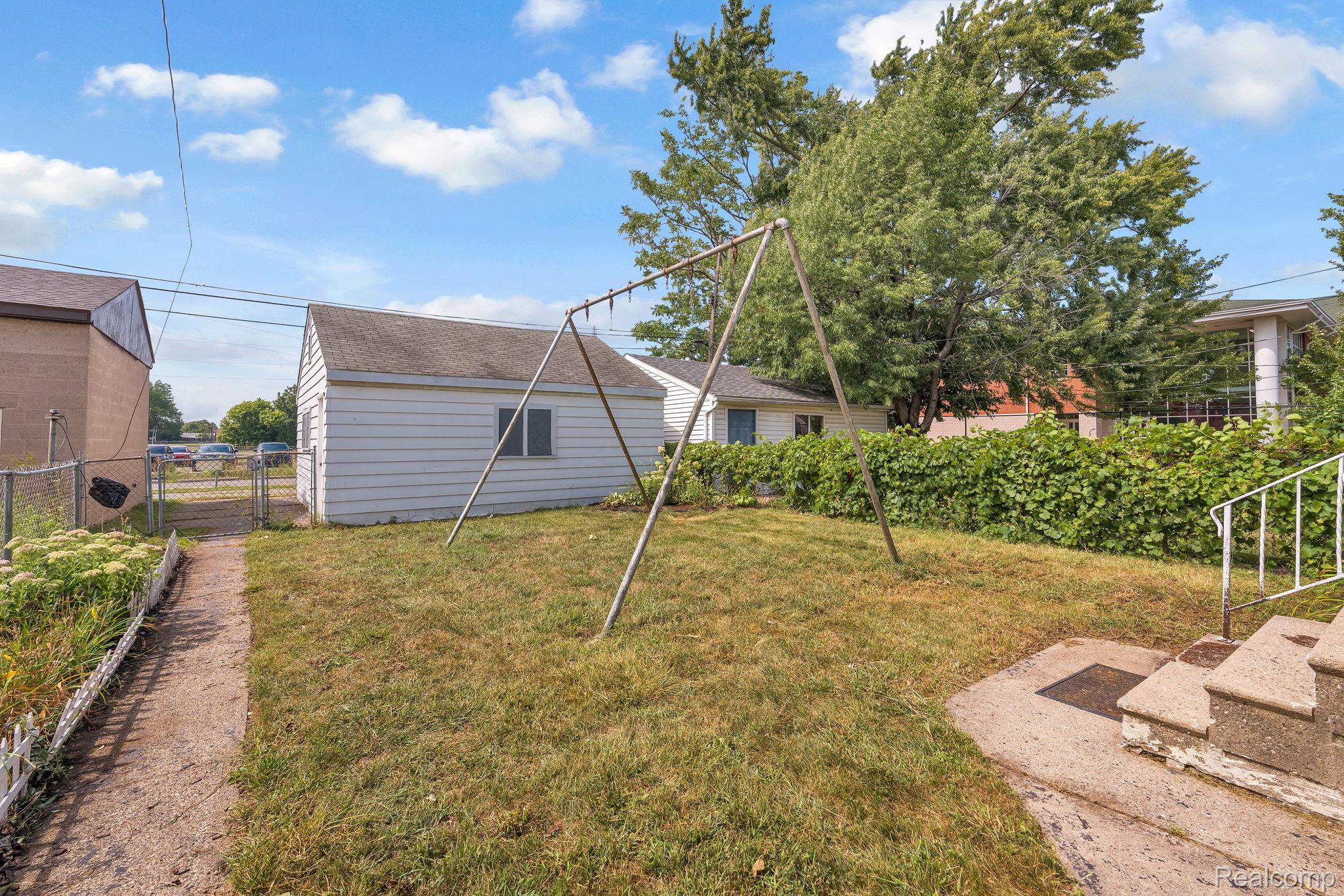 7631 Maple Street Dearborn, MI 48126 - Photo 43 of 48 Fenced backyard with a detached garage, concrete steps, and a path leading to a chain-link gate