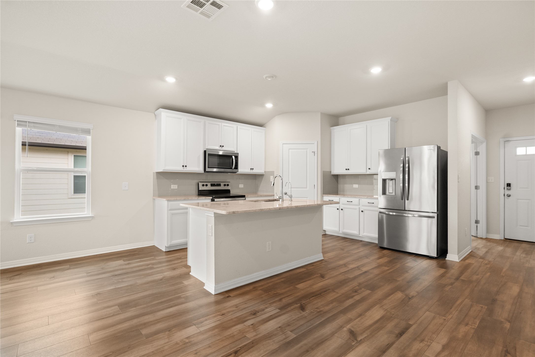 105 Saviano Road Hutto, TX 78634 - Photo 3 of 22 A well-lit kitchen with wood flooring and an inviting island awaits your culinary adventures.