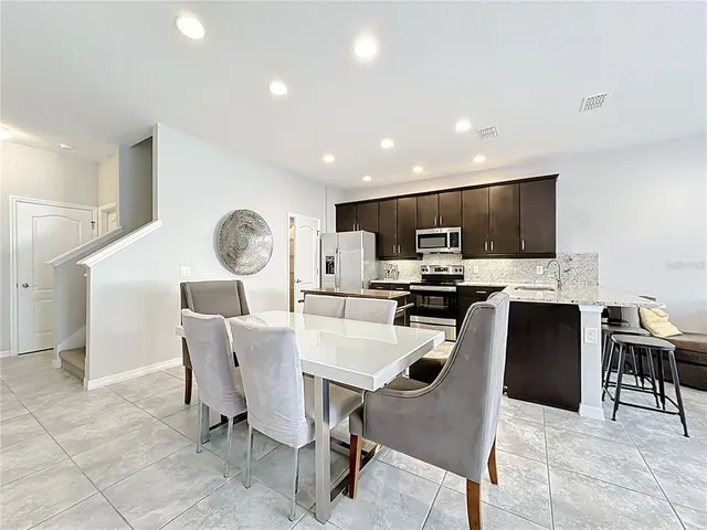 a view of kitchen with refrigerator stove dining table and chairs