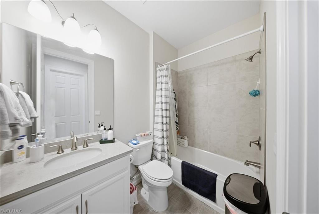 1074 Enbrook Loop Naples, FL 34114 - Photo 12 of 36 a bathroom with a granite countertop toilet a sink a mirror a shower and vanity