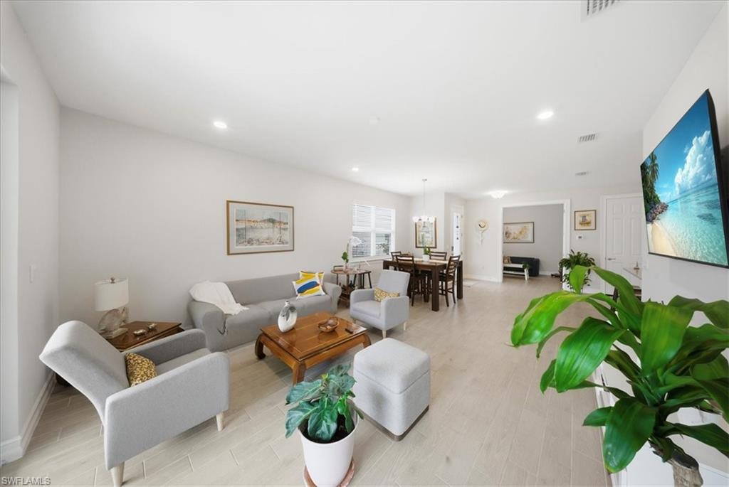 1074 Enbrook Loop Naples, FL 34114 - Photo 13 of 36 a living room with furniture a chandelier and a flat screen tv