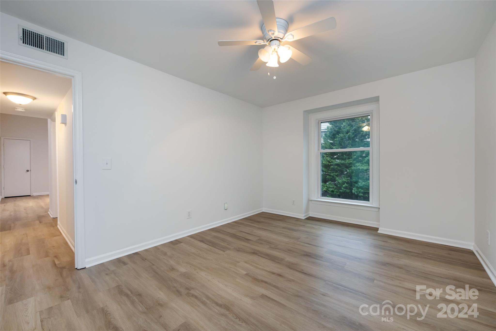 430 Queens Road, Unit 231 Charlotte, NC 28207 - Photo 14 of 23 an empty room with wooden floor fan and windows