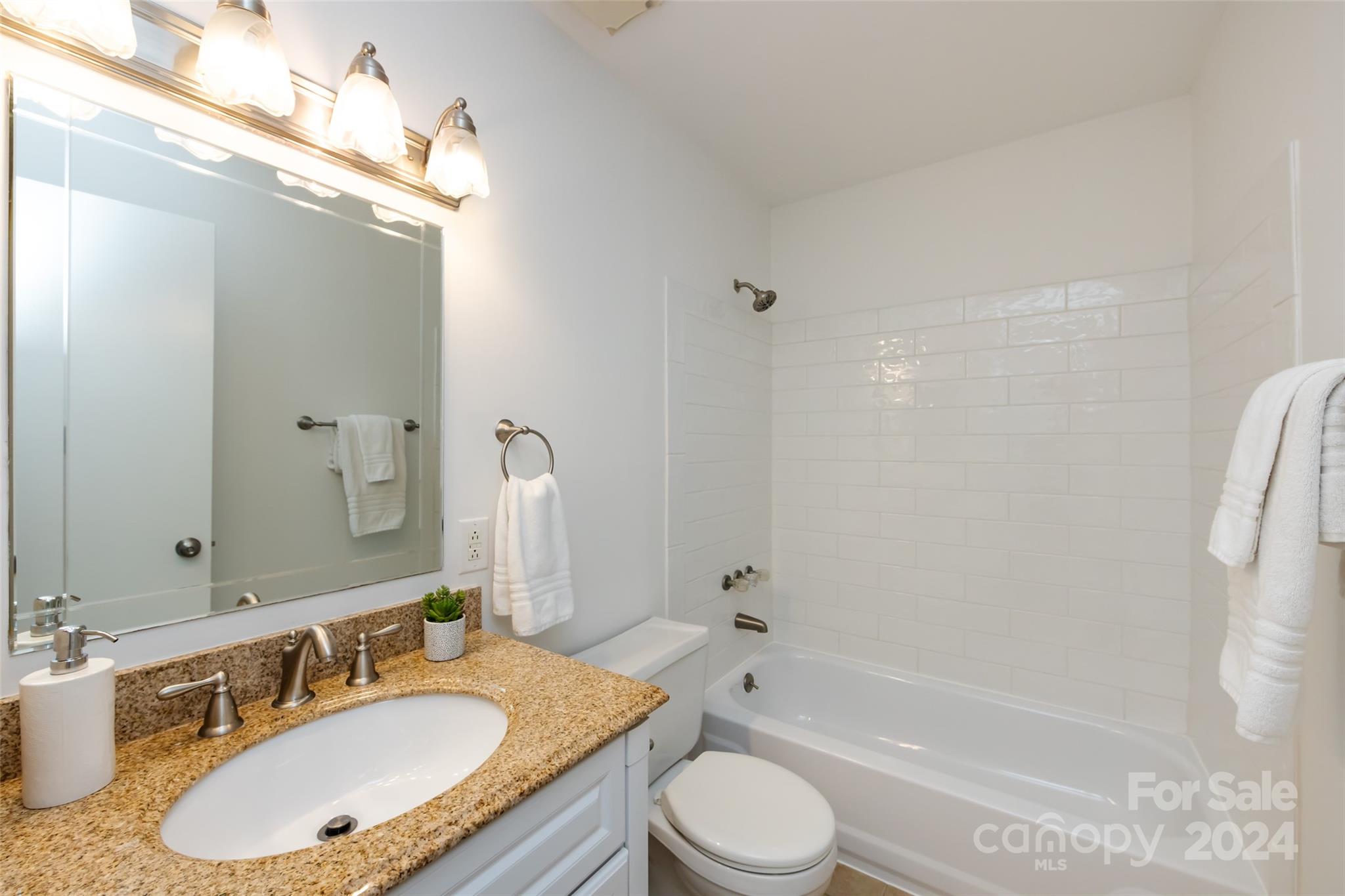430 Queens Road, Unit 231 Charlotte, NC 28207 - Photo 21 of 23 a bathroom with a granite countertop sink toilet mirror and shower