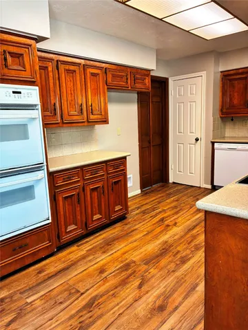 a view of a kitchen with wooden floor and cabinets