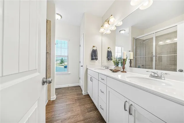 a spacious bathroom with a double vanity sink a mirror and a shower